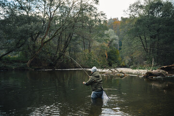 Fototapeta na wymiar Fly fisherman casting with artificial flies on the river during autumn.