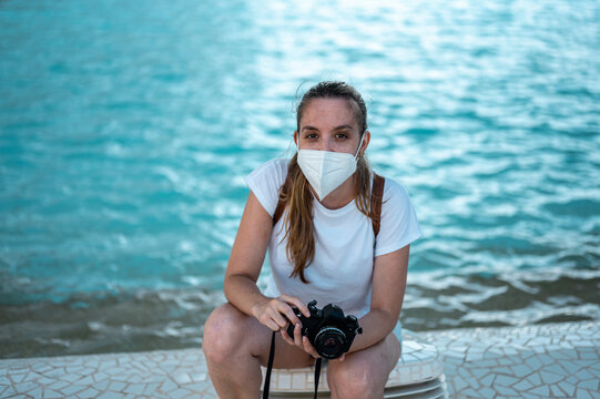 Young and pretty girl with FPP2 mask taking pictures with an analog camera in the science park of Valencia