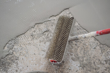 plasterer during floor covering works with self-levelling cement mortar, uses a needle roller