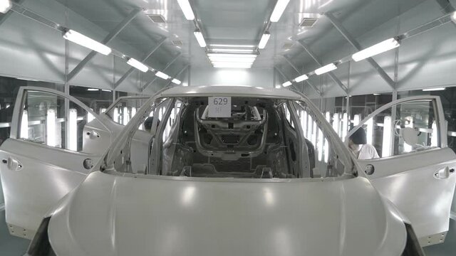 Checkman are checking assembling of car bodies before painting process. Car manufacturing factory.