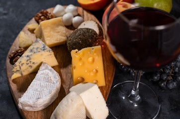 Pieces of aromatic parmesan and black raisins grapes on a dark background. Wine plate.