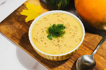 Bowl of vegetable cream soup with pumpkin and herbs.