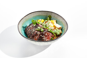 Traditional oriental food - fried rice with egg and beef. Stir-fry rice in asian style on white background. Meat and rice with omelette in bowl. Isolated on white background.