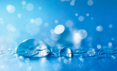 Transparent water drops in blue color with bokeh and copy space in macro