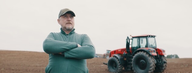 Hero shot portrait of 50s farmer posing against tractor early in the morning in the field © supamotion