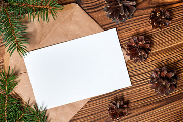 Open envelope with blank letterhead on wooden background with Pine cones and fir branches