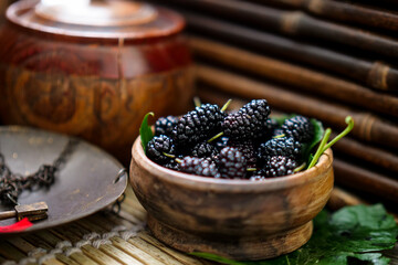 Ripe black mulberries in summer, freshly picked in wooden bowl