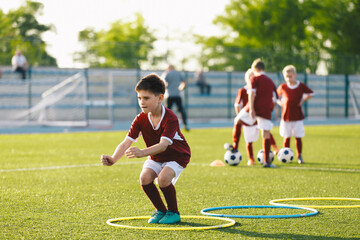 Obraz premium Young Boys on Physical Education Outdoor Class. Kids Jumping High Into Hula Hoops. Soccer Team on Training Unit.