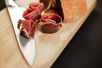 beef basturma with a knife on a board in spices