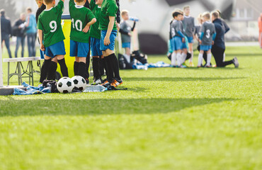 Children in two soccer teams standing in groups with young school coaches. Group of kids in football treams on soccer tournament. Happy kids playing football games