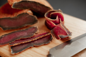 beef basturma with a knife on a board in spices
