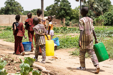 Group of black African children carrying empty water containers on their way home from the village...