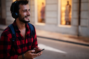 Young man listening to music. Urban fashion man with headphones enjoying the city