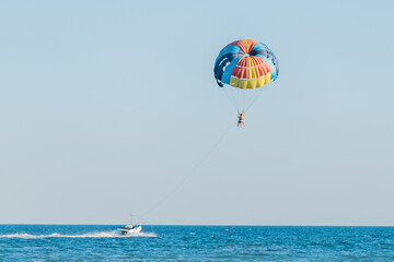 Fototapeta na wymiar Ukraine, Iron Port - August 31, 2020: Extreme sports and exciting rest activity. Vacationing tourists fly on a parashute over the sea against the background of blue sky and horizon line