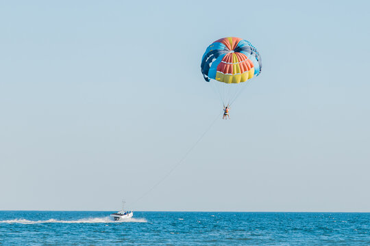 Ukraine, Iron Port - August 31, 2020: Extreme sports and exciting rest activity. Vacationing tourists fly on a parashute over the sea against the background of blue sky and horizon line