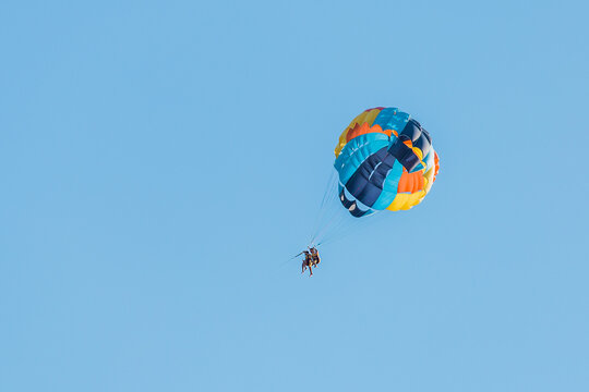 Ukraine, Iron Port - August 31, 2020: Extreme sports and exciting rest activity. Vacationing tourists fly on a parashute in blue sky background