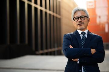 Portrait of senior businessman with crossed arms. Handsome man in suit outdoors.