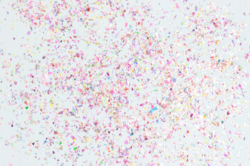 Holographic colorful confetti on a blue pastel background. Multicolored backdrop.