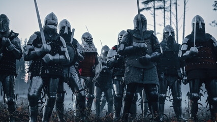 Epic Invading Army of Medieval Knights on Battlefield. Armored Soldiers in Helmets, With Shields and Swords ready for the Battle. War, Conquest, Crusade. Historical Reenactment. - obrazy, fototapety, plakaty