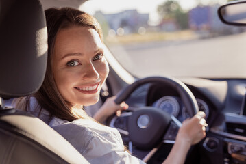 Fototapeta na wymiar Photo of sweet charming young lady dressed white shirt smiling driving automobile outdoors urban route