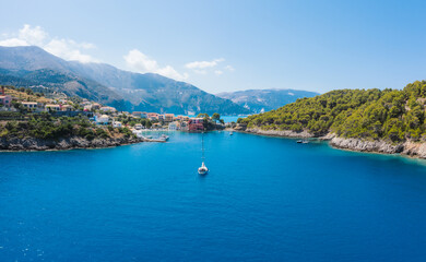 Fototapeta premium Assos picturesque fishing village from above, Kefalonia, Greece. Aerial drone view. Sailing boats moored in turquoise bay