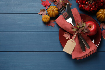 Festive table setting with autumn decor on blue wooden background, flat lay. Space for text