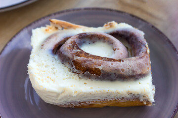  piece of a serving of a sweet cinnamon bun with cinnabon cream lies on a beautiful plate, fresh homemade cakes