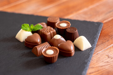 Group of different chocolates, milk and dark, on a black background.