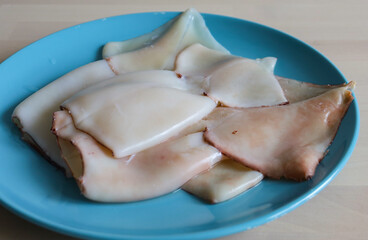 the squid carcass lies on a plate on the table. Proper nutrition, protein, seafood, affordable squid meat, raw food diet