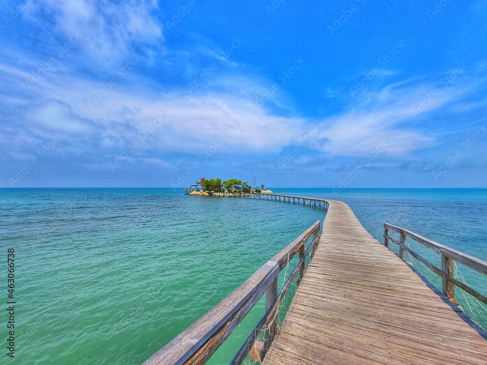 Sticker Wooden pier over the wavy sea under a blue sky with tiny clouds