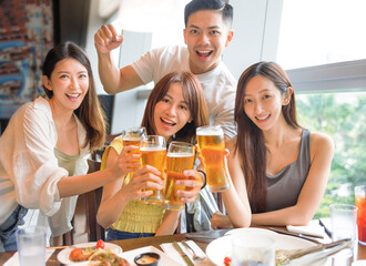 Young friends enjoying food and drink in restaurant