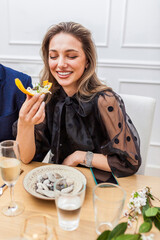 Portrait of a stylish beautiful woman eating a canape at private dinner party at home. Woman eating...