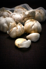 Head and mesh of garlic on a dark background, vertical frame