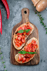 Two bruschetta with chopped tomatoes, basil and pesto sauce on wooden board. Toast with ciabatta and tomatoes