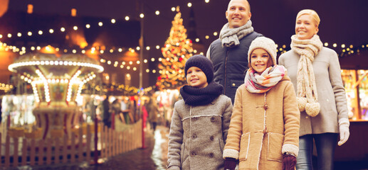 winter holidays, leisure and people concept - happy family over evening christmas market or...