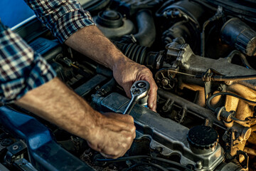 Fototapeta premium Repairman's male hands with a wrench. Vehicle fitter inspecting used car engine