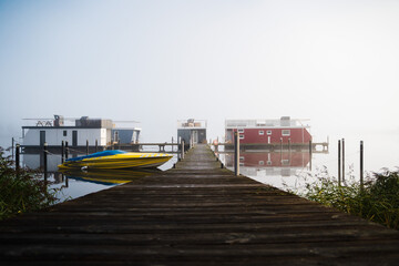 Fototapeta premium Steg mit Hausbooten im Nebel am Morgen in Schleswig