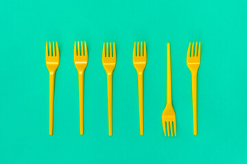 Yellow disposable forks lying on the blue background