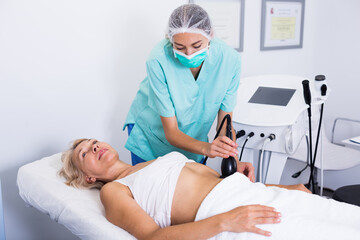 Obraz premium Woman receiving innovative procedure of cryoliposuction in clinic of esthetic cosmetology