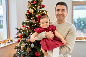 winter holidays and family concept - happy middle-aged father and baby daughter over christmas tree at home