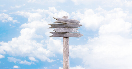 Four old wooden arrow pointers on a background of sky and clouds