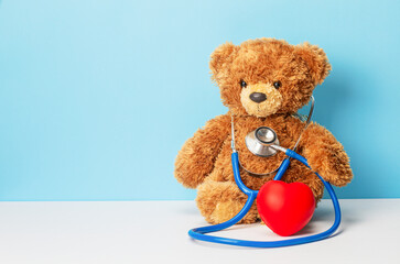 Teddy bear and stethoscope with a heart. Treatment of children, pediatrics. Teddy bear on a blue...