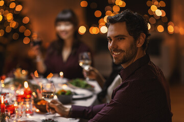 holidays, party and celebration concept - happy smiling man having christmas dinner with friends at home