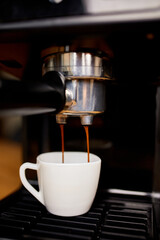 Detail of a professional coffe maker dripping coffe into an empty cup in a cafeteria, Machine is making a perfect coffee with delicious smell, . Espresso Coffee Machine Making Espresso Coffee