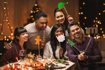 holidays, party and celebration concept - multiethnic group of happy friends having christmas dinner at home and taking selfie with smartphone