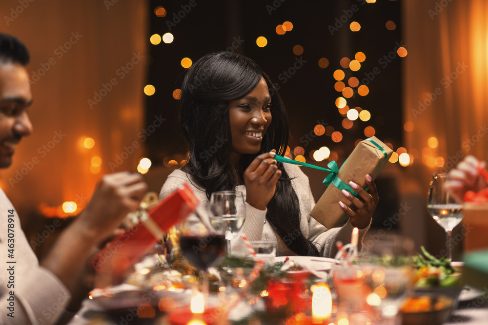 Wall mural holidays, party and celebration concept - multiethnic group of happy friends having christmas dinner