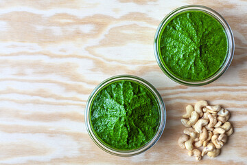 Bowl with green chutney sauce dip from leaves with cashew nuts. Top view with copy space.
