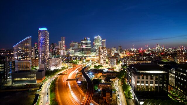 London skyline at dusk time-lapse view from a tall skyscraper with motorway and DLR traffic in foreground
