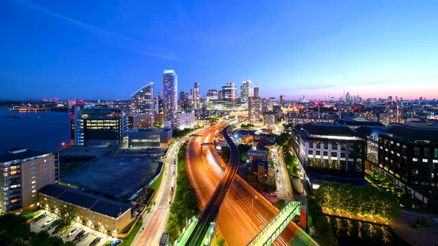 Iconic London skyline dusk to night time-lapse view of skyscraper clusters with a busy motorway in the foreground from an elevated viewpoint