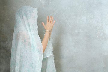 a woman folded her arms over her chest in a prayer pose with a closed head with a cloth